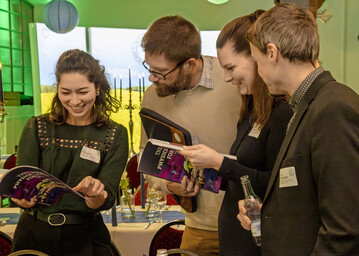 Forschende des Leibniz-Instituts für Plasmaforschung und Technologie e. V. betrachten das bei der Abschlussveranstaltung am 19. November 2025 in Neubrandenburg veröffentlichte Magazin „The Physics for Food Story“.