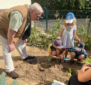SVLFG-Vorstandsmitglied Dr. Volker Wolfram schaut den Kindern beim Pflanzen zu.