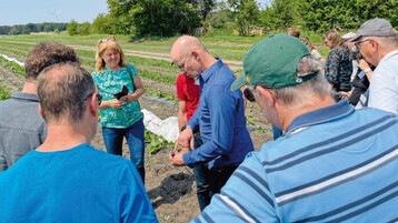 Christoph Knösels erläutert auf dem Feld die Funktionsweise der Tropfschläuche.